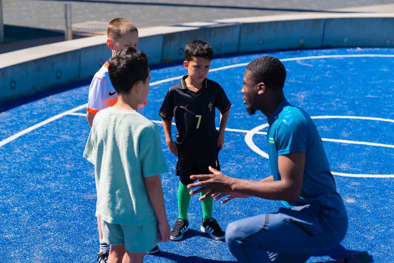 begeleider legt iets uit aan drie kinderen op het veld. Elke dag leren we iets nieuw