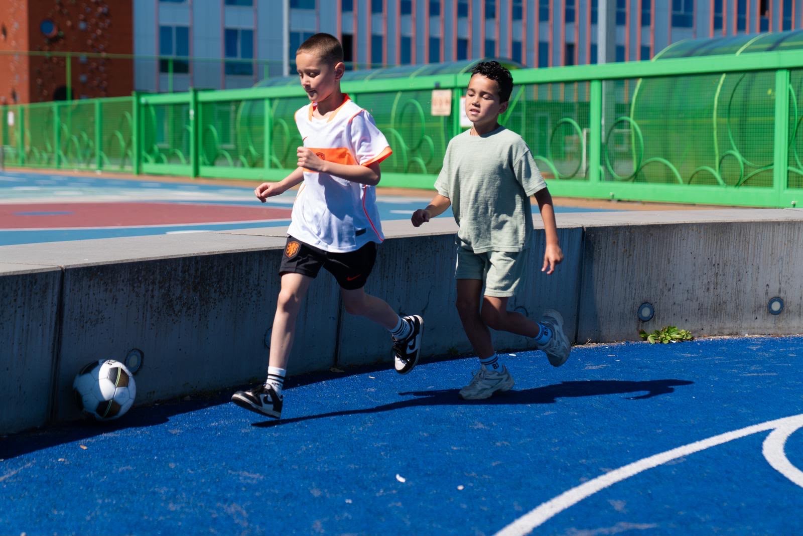 twee kinderen rennen achter de bal aan. Gewoon lekker rennen en spelen
